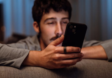 Man looking at smartphone with Oura Ring