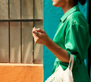 Woman in green dress carrying white bag