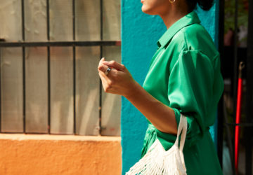 Woman in green dress carrying white bag