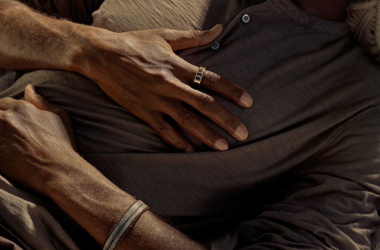 Man sleeping with hands on chest wearing an Oura Ring. Sleep Apnea, Defined — And How to Treat It.