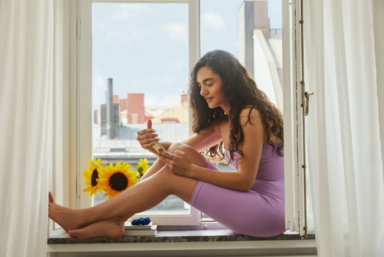 Oura x Natural Cycles: Woman Checking Fertility App Sitting in Windowsill