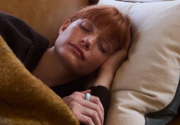 Woman resting on couch wearing Oura Ring 4 Ceramic