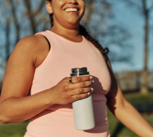 Woman walking holding water bottle and wearing Oura Ring