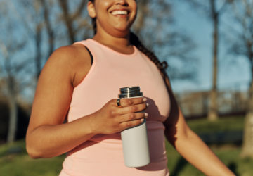 Woman walking holding water bottle and wearing Oura Ring