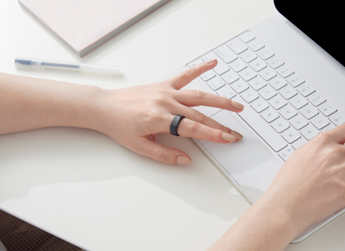 Hand on computer keyboard wearing Oura Ring.