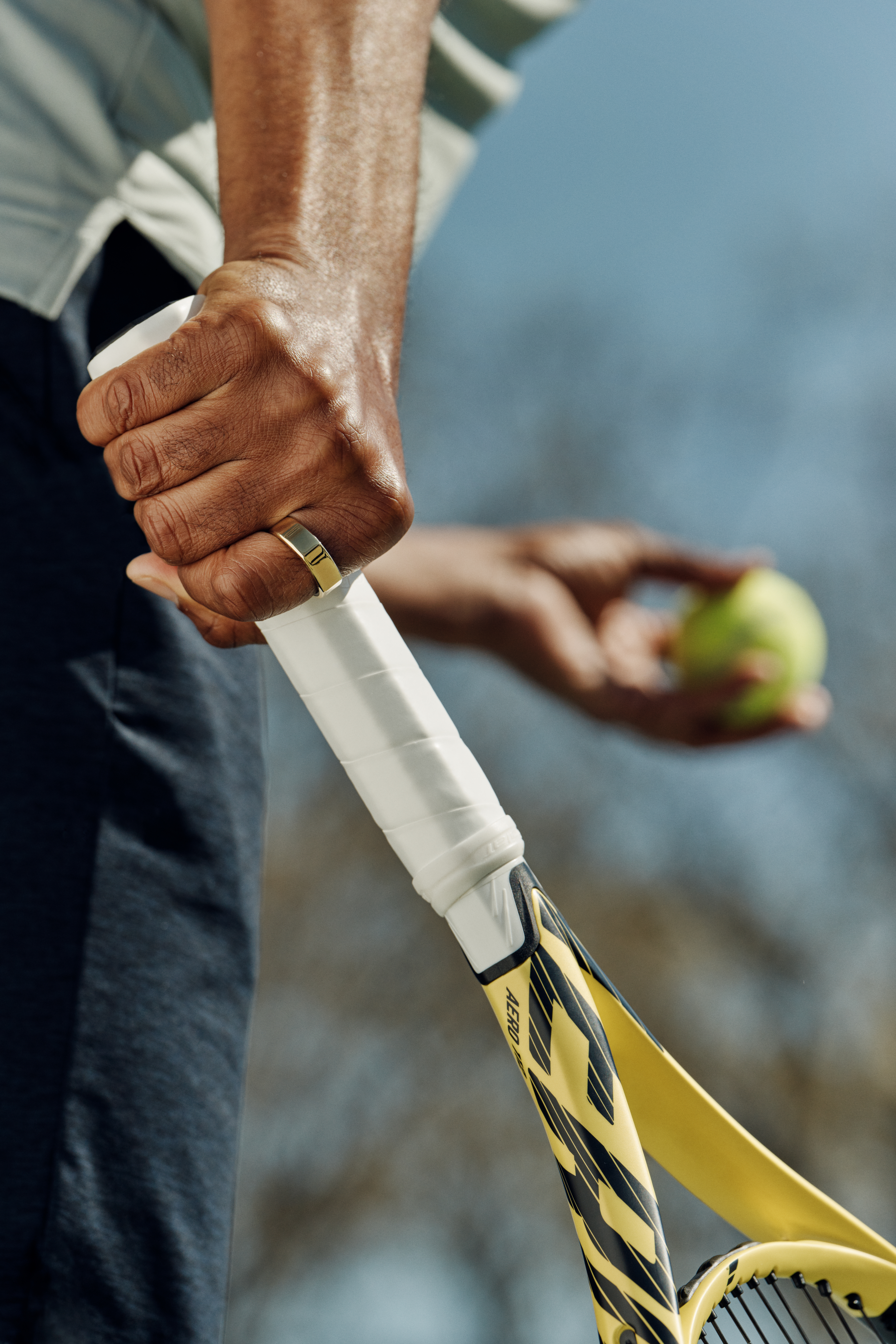 Man playing tennis wearing gold Oura Ring