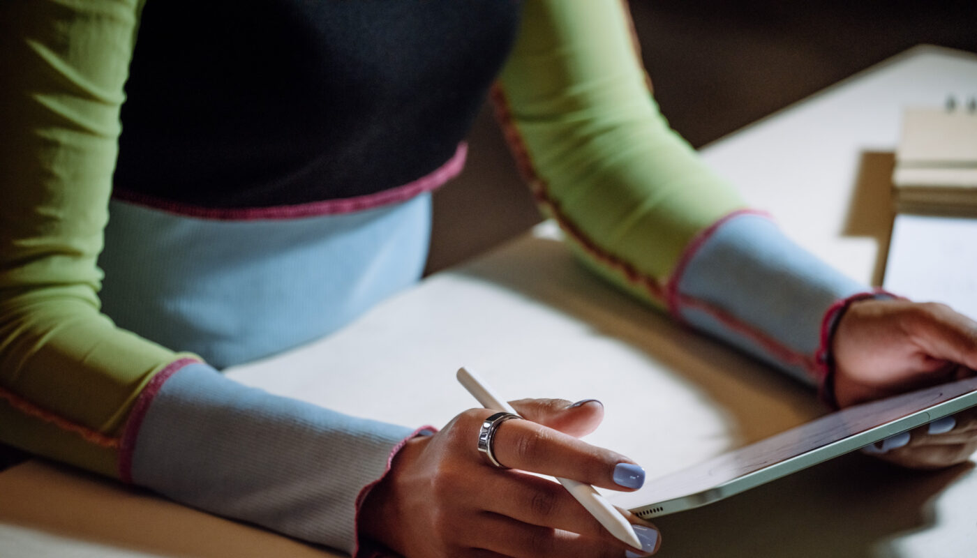 Woman writing on iPad wearing an Oura Ring