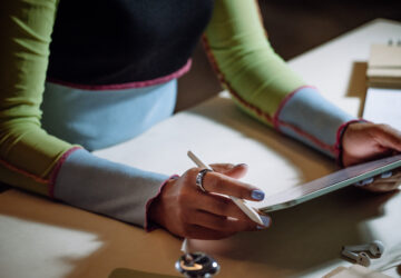 Woman writing on iPad wearing an Oura Ring