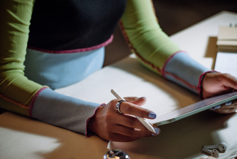 Woman writing on iPad wearing an Oura Ring