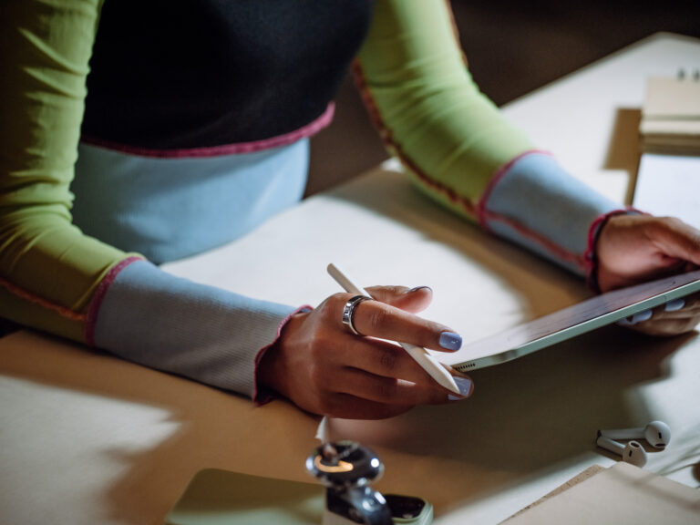 Woman writing on iPad wearing an Oura Ring