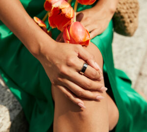 Woman wearing a green dress and Oura Ring holding a flower