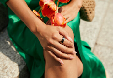Woman wearing a green dress and Oura Ring holding a flower