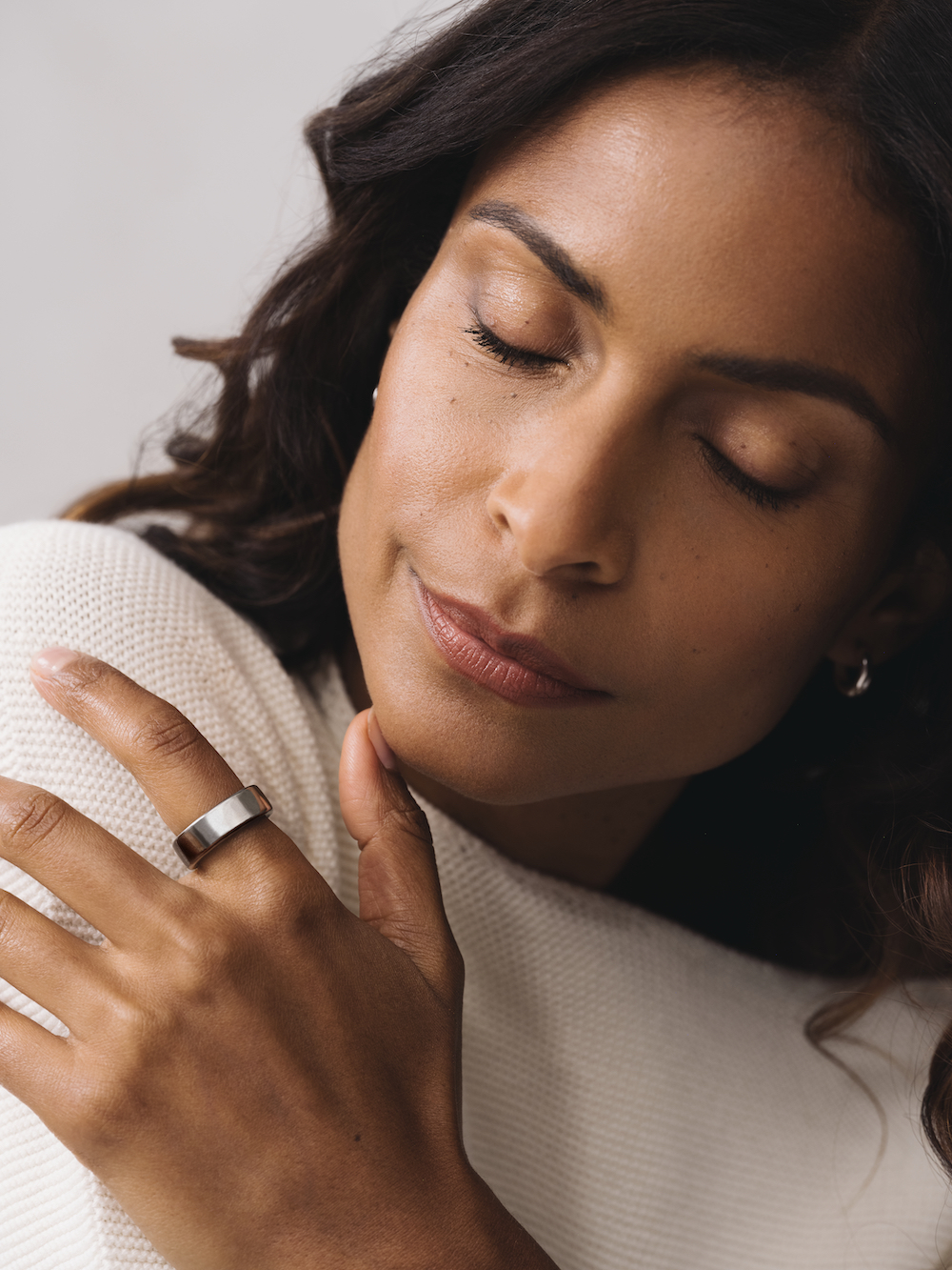 Woman wearing white sweater and Oura Ring