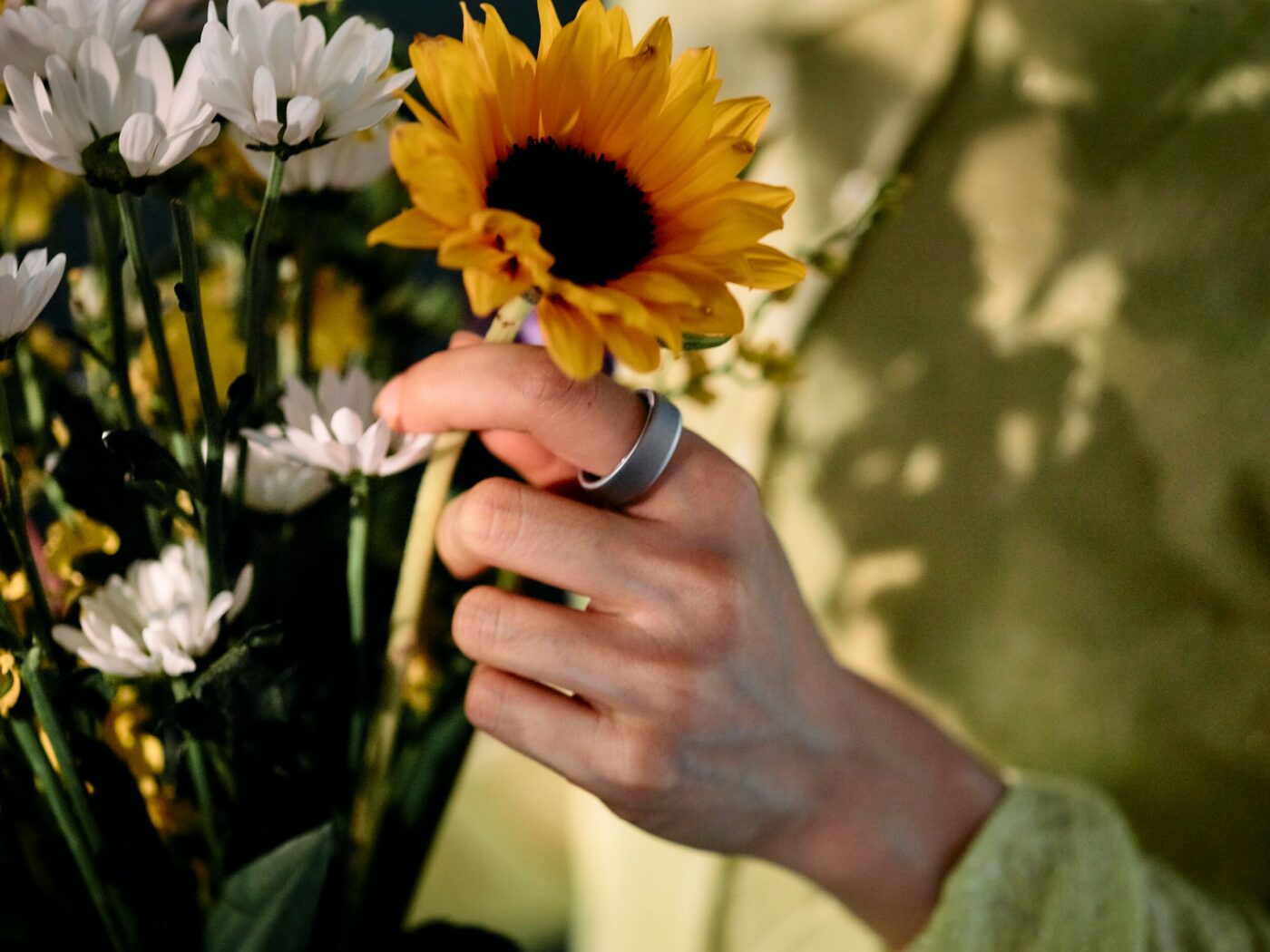 Woman picking a sunflower wearing Oura Ring 4