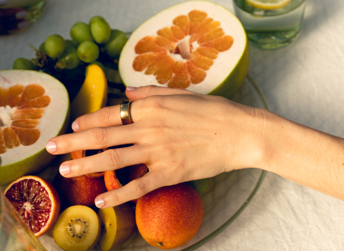 Woman wearing gold Oura Ring with a fruit bowl