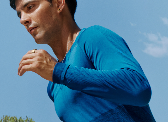 Man wearing blue shirt running with Oura Ring