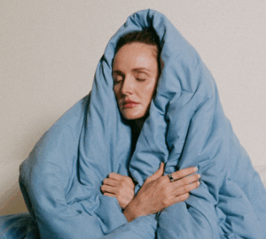 Woman wrapped in blue blanket wearing Oura Ring