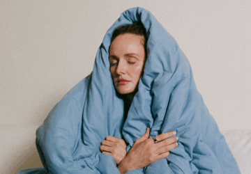 Woman wrapped in blue blanket wearing Oura Ring