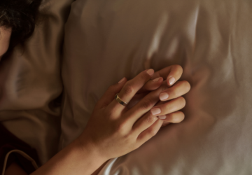 Person laying in bed with an Oura Ring 5 on their finger