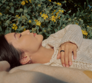Person lying in a field wearing an Oura Ring with hand across chest