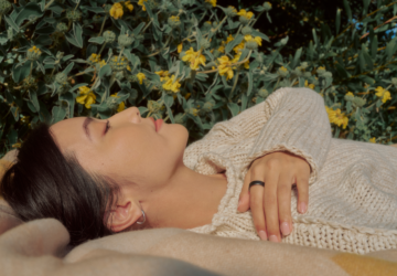 Person lying in a field wearing an Oura Ring with hand across chest