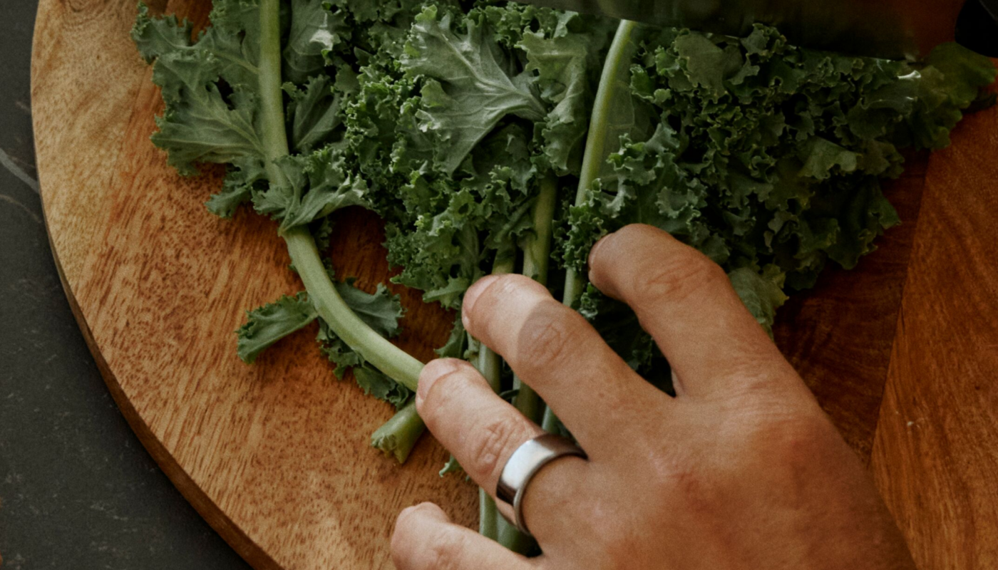 Man wearing Oura Ring chopping kale
