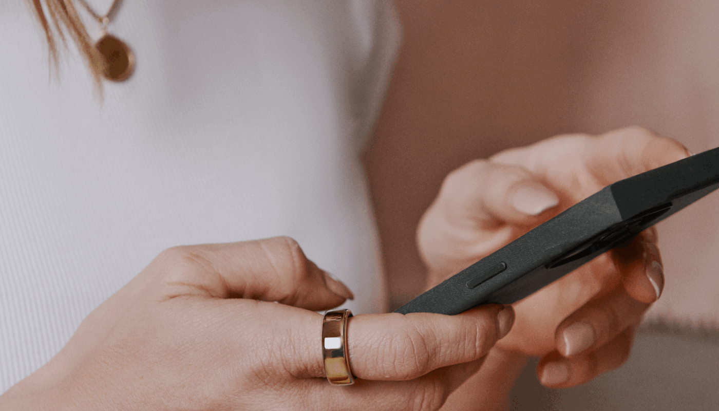 Woman looking at phone wearing Oura Ring