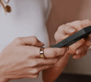 Woman looking at phone wearing Oura Ring