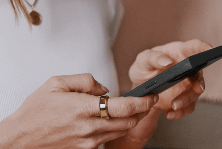 Woman looking at phone wearing Oura Ring