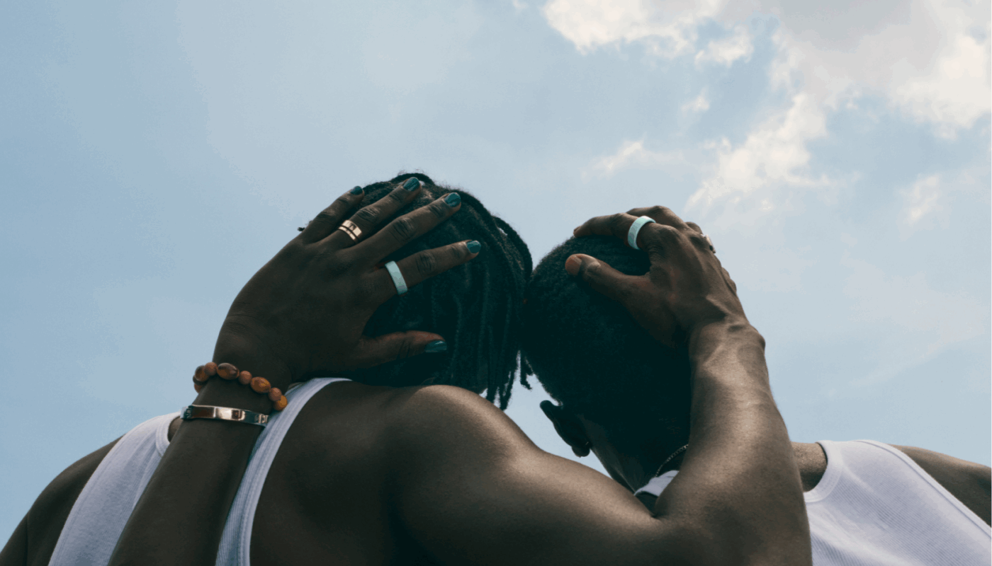 Two men embracing wearing Oura Ring 4 Ceramic in Tide