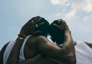 Two men embracing wearing Oura Ring 4 Ceramic in Tide