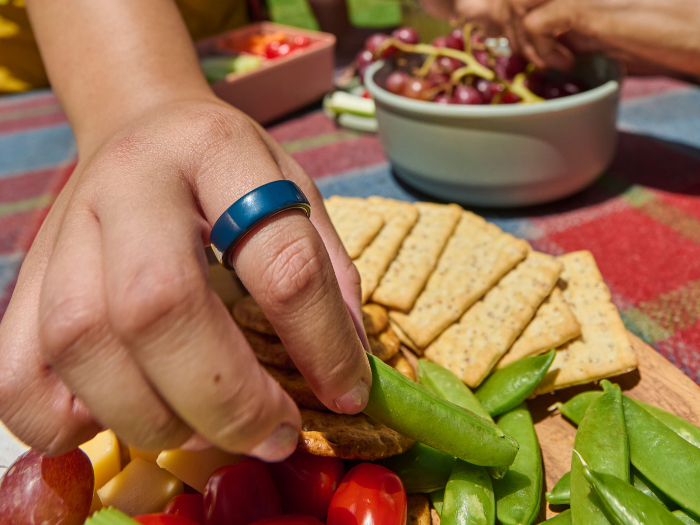 Person wearing Oura Ring 4 Ceramic - Midnight reaching for vegetables