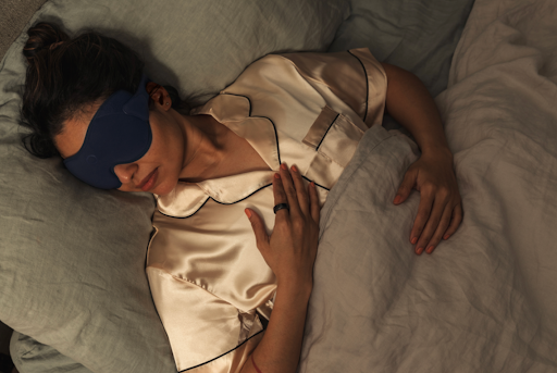 Woman sleeping with sleep mask and Oura Ring