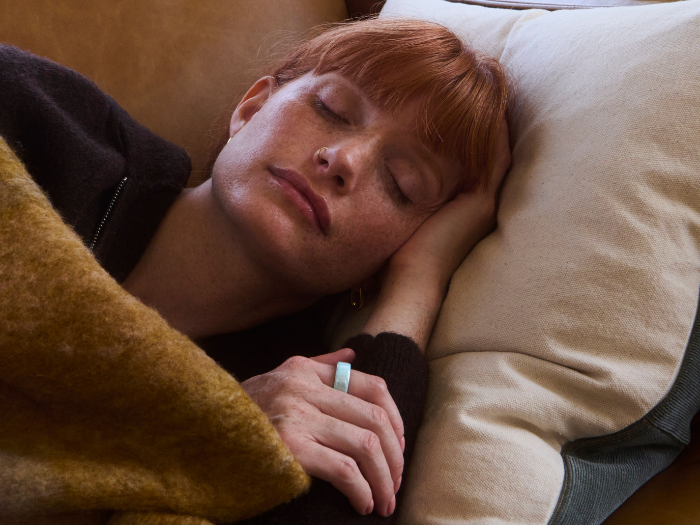 Woman sleeping on couch wearing Oura Ring 4 Ceramic