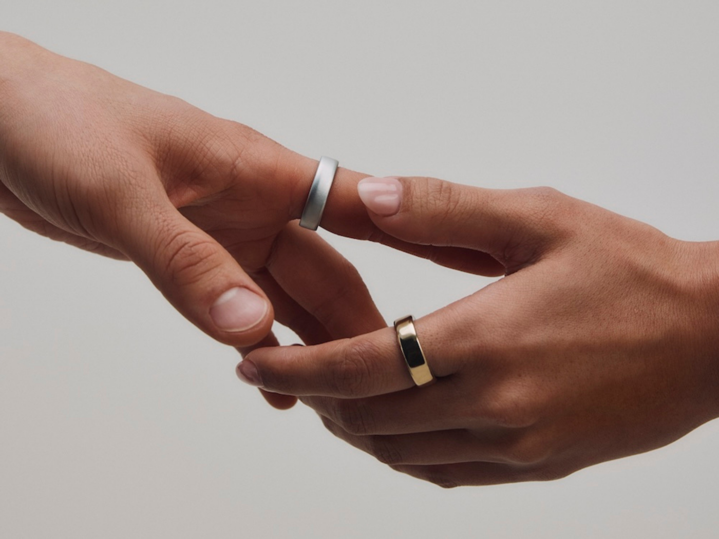 Two people wearing Oura Ring 5 in Brushed Silver and Gold