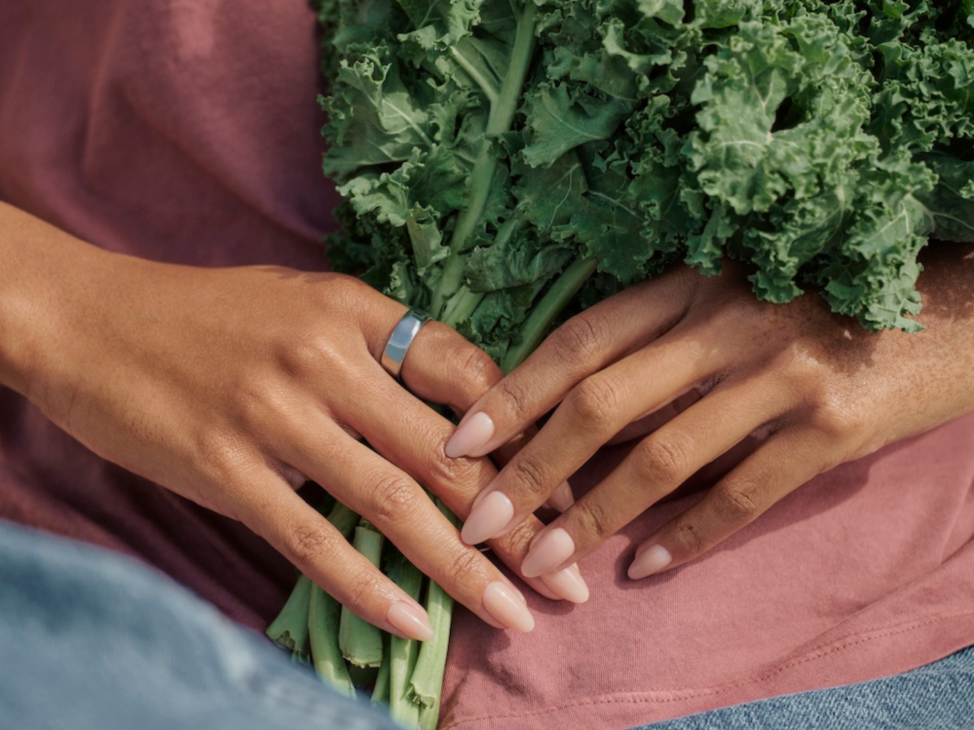 Woman holding bunch of kale wearing Oura Ring 5