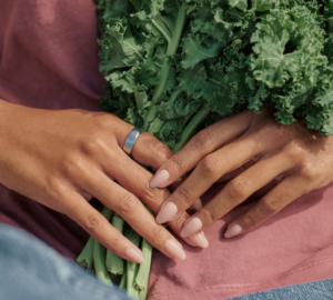 Woman holding bunch of kale wearing Oura Ring 5
