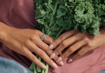 Woman holding bunch of kale wearing Oura Ring 5