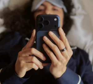 Person looking at phone screen lying in bed wearing Oura Ring 5