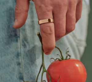 Person wearing Oura Ring 5 in Deep Rose holding a tomato