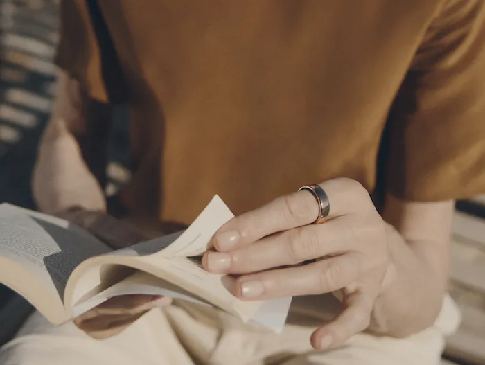 Woman wearing Oura Ring and reading a book