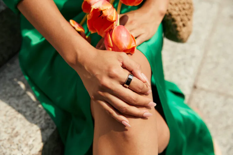 Woman wearing a green dress and Oura Ring holding a flower