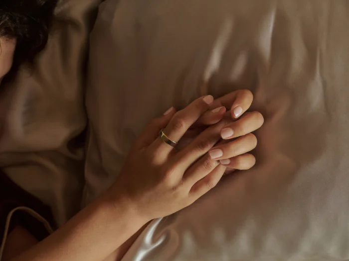 Person laying in bed with an Oura Ring 5 on their finger