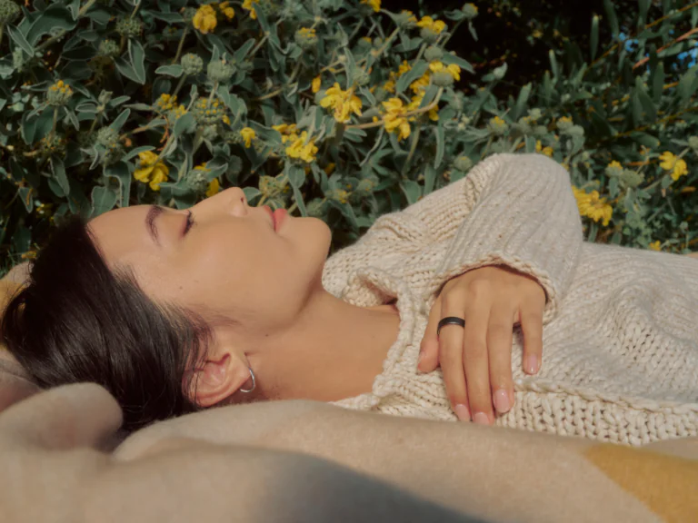Person lying in a field wearing an Oura Ring with hand across chest