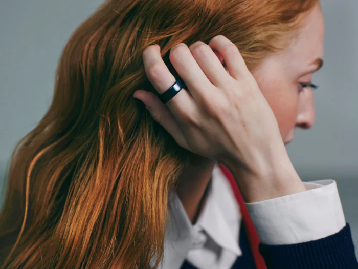 Woman with red hair wearing Oura Ring 4 Ceramic in Midnight