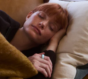 Woman sleeping on couch wearing Oura Ring 4 Ceramic