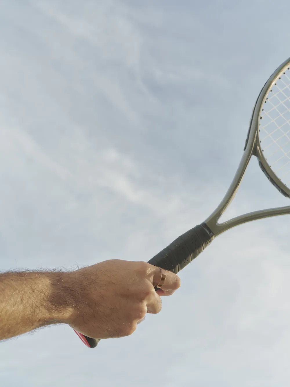 Person holding tennis racket wearing Oura Ring 5